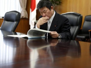 Japan's Economy, Trade and Industry Minister Motegi reads IAEA review report on TEPCO's tsunami-crippled Fukushima Daiichi nuclear power plant after he received it from Lentijo, head of review mission from IAEA in Tokyo